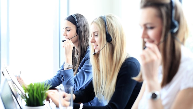 Ritratto di un'addetta al call center accompagnata dal suo team. Operatore di assistenza clienti sorridente al lavoro.