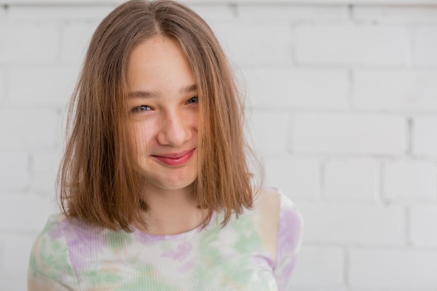 Ritratto di un'adolescente snella in un dolcevita leggero alla luce naturale contro un muro di mattoni bianchi. bellezza naturale, senza trucco. pelle problematica. spazio per il testo. Foto di alta qualità