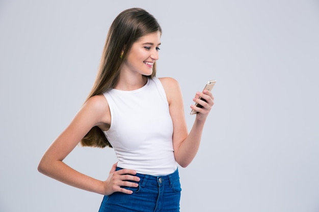 Ritratto di un'adolescente sorridente che utilizza smartphone isolato