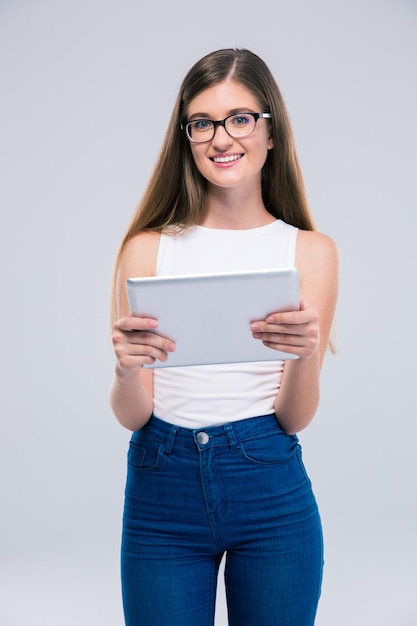 Ritratto di un'adolescente sorridente con gli occhiali che tiene il computer tablet isolato