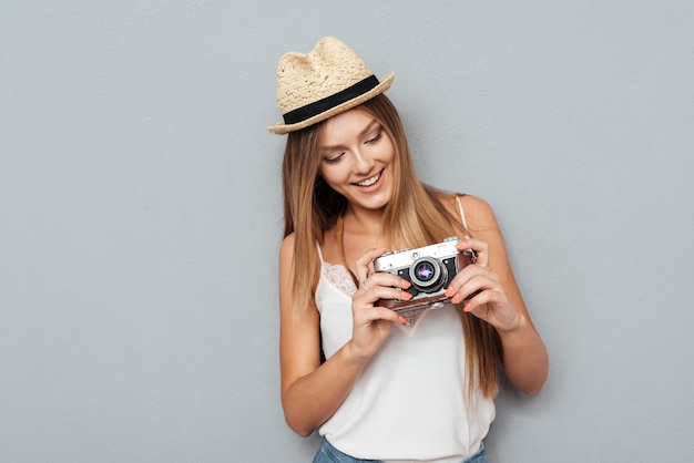 Ritratto di un'affascinante donna sorridente in cappello guardando la fotocamera retrò isolata su uno sfondo grigio