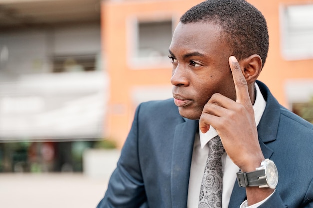 Ritratto di un africano in città con la mano sul viso pensando