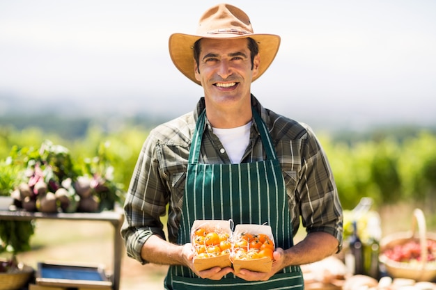 Ritratto di un agricoltore sorridente che tiene scatola di frutta