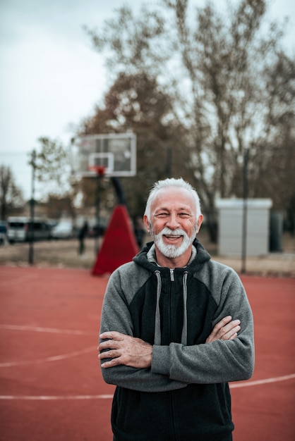 Ritratto di un anziano sportivo. Braccia incrociate, guardando la telecamera.