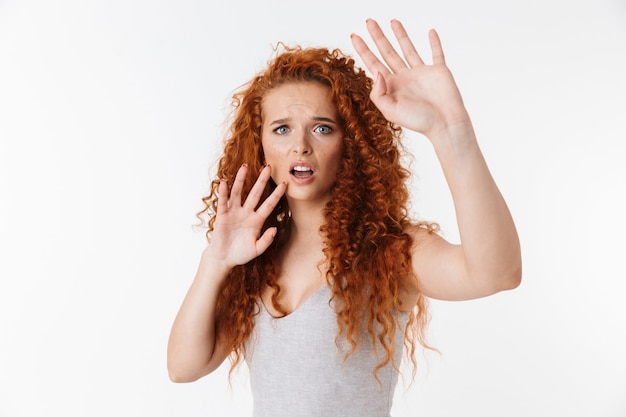 Ritratto di un'attraente giovane donna spaventata con lunghi capelli rossi ricci in piedi isolata