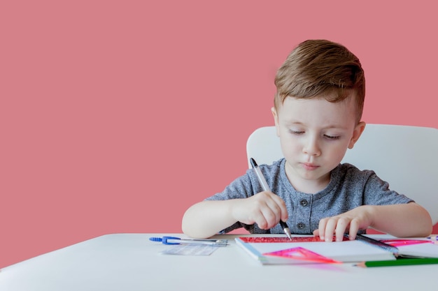 Ritratto di un bambino carino a casa che fa i compiti a casa Un bambino concentrato che scrive con una matita colorata in casa Scuola elementare e istruzione Un bambino che impara a scrivere lettere e numeri