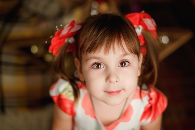 Ritratto di un bambino carino con illuminazione di luci di Natale su sfondo Close up piccola ragazza