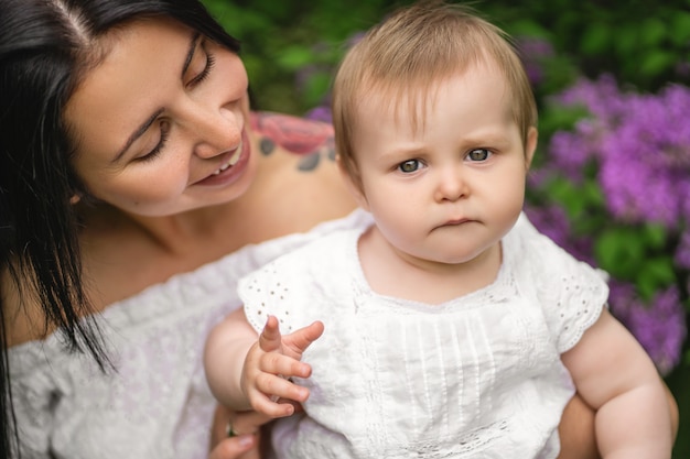 Ritratto di un bambino carino, facendo buffo viso curioso, trattenuto da sua madre