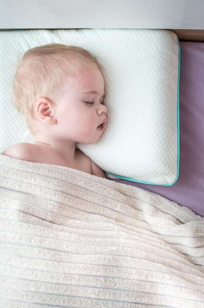 Ritratto di un bambino che dorme in un letto su un cuscino. Foto verticale