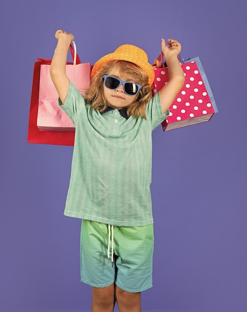 Ritratto di un bambino con una borsa della spesa su uno sfondo blu isolato ritratto di una bambina con borse della spesa