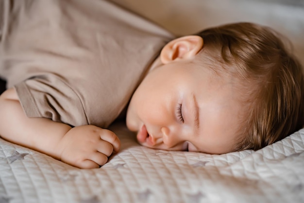 Ritratto di un bambino divertente che dorme a pancia in giù sul letto di casa Primo piano