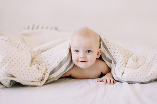 Ritratto di un bambino felice che si nasconde sotto la coltre bianca.