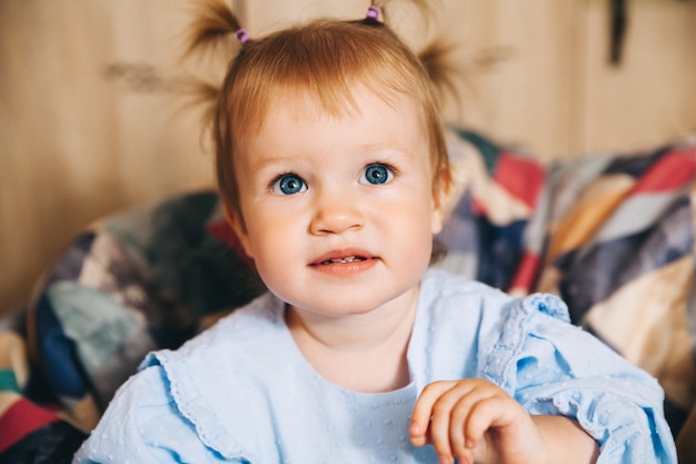 Ritratto di un bambino felice, una bambina è seduta su una sedia morbida. Bambino felice di 1 anno.