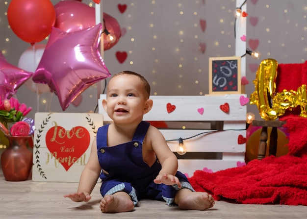 Ritratto di un bambino in una cabina dei baci decorata con cuori e palloncini