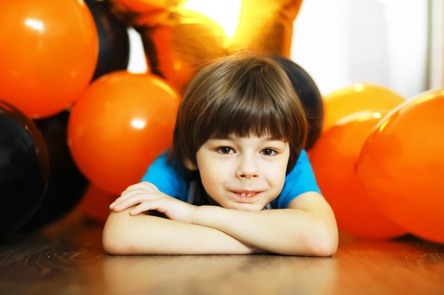 Ritratto di un bambino piccolo sdraiato sul pavimento in una stanza decorata con palloncini. Concetto di infanzia felice.