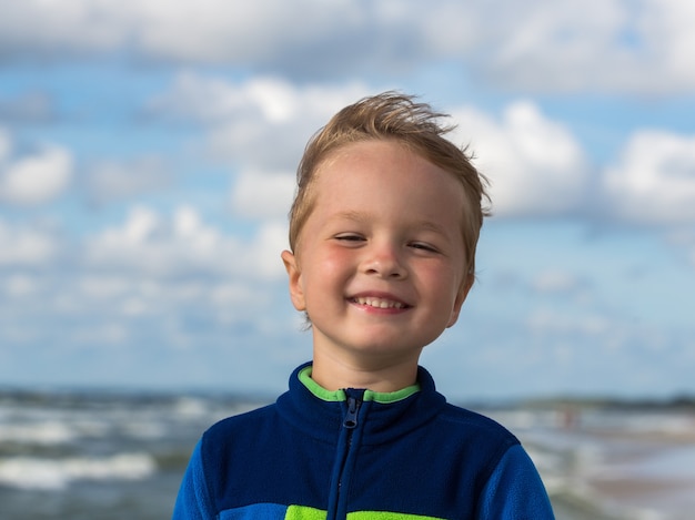 Ritratto di un bambino sorridente felice sul Mar Baltico