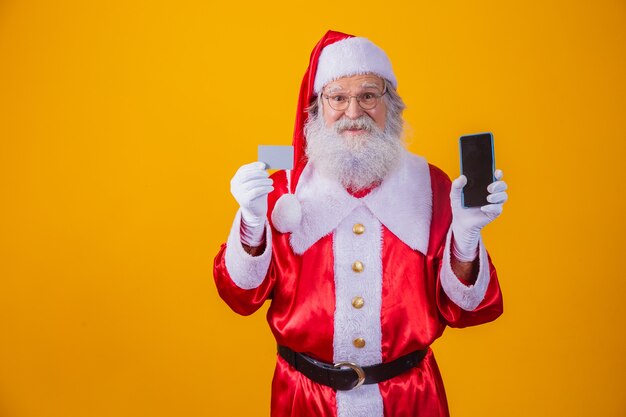 Ritratto di un bel Babbo Natale in possesso di carta di credito e smartphone con schermo vuoto per il testo in mano.