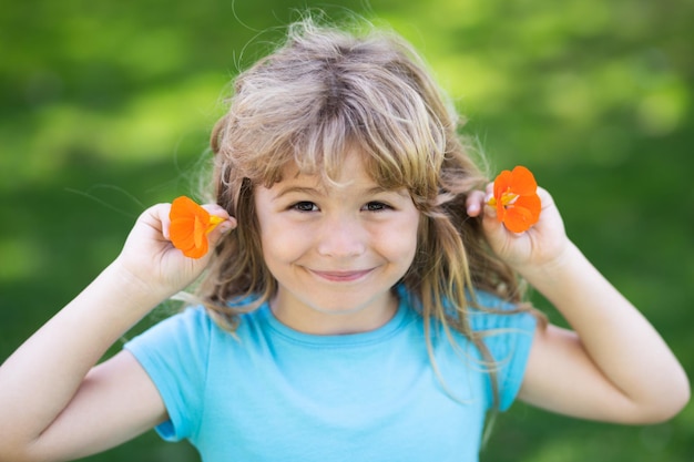 Ritratto di un bel bambino nel giardino estivo in fiore Bambino felice sul prato con fiori bianchi Calda serata estiva Bambini e natura