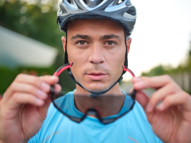 Ritratto di un bel giovane ciclista maschio che guarda la telecamera mentre si tiene in mano una protezione