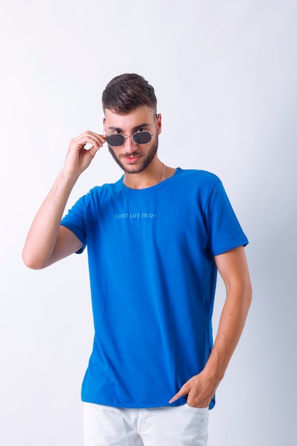 Ritratto di un bel giovane modello alla moda sorridente vestito con la posa dell'uomo di moda blueTshirt