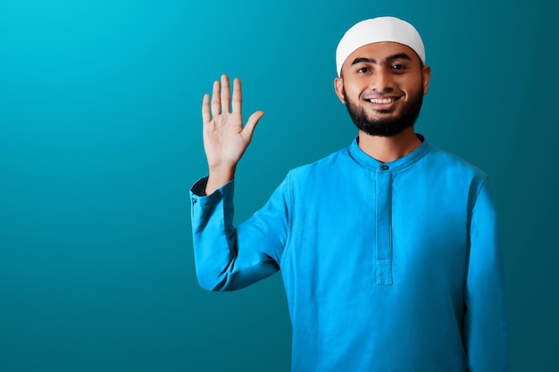 Ritratto di un bel giovane uomo musulmano asiatico con la barba che dice ciao agitando il gesto della mano