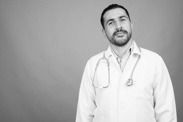 Ritratto di un bel medico persiano barbuto su grigio in bianco e nero