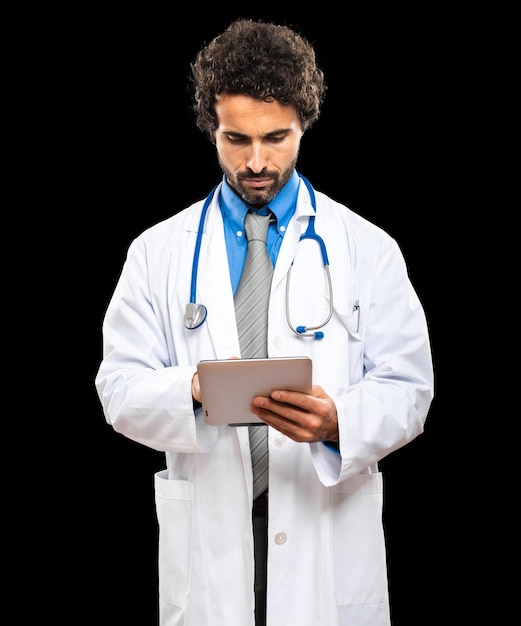 Ritratto di un bel medico utilizzando una tavoletta digitale isolata sul nero