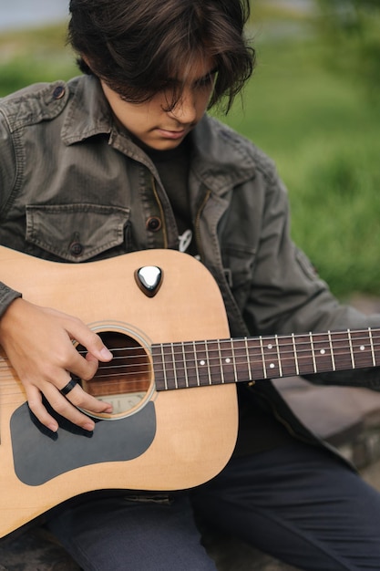 Ritratto di un bel ragazzo che suona la chitarra ragazzo all'aperto che usa solo la chitarra classica maschio che fa