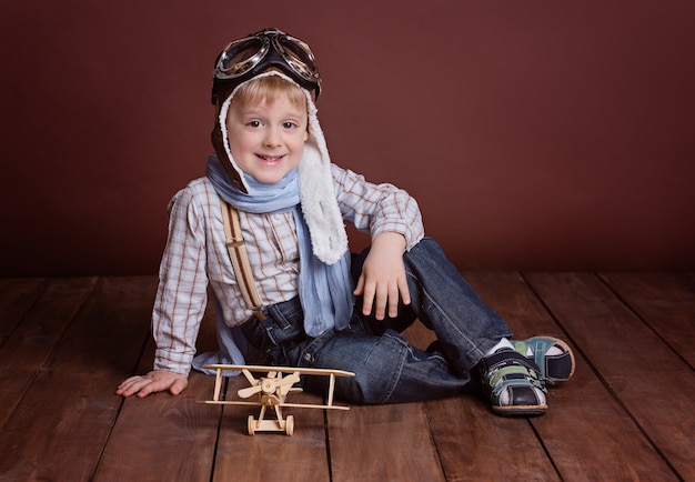 Ritratto di un bel ragazzo in un casco da pilota con un aereo di legno