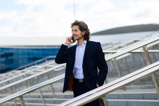 Ritratto di un bel uomo d'affari con telefono, tazza di caffè per le strade della città