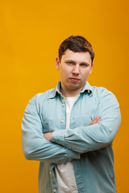 Ritratto di un bell'uomo europeo in camicia che guarda l'obbiettivo in piedi su sfondo giallo studio