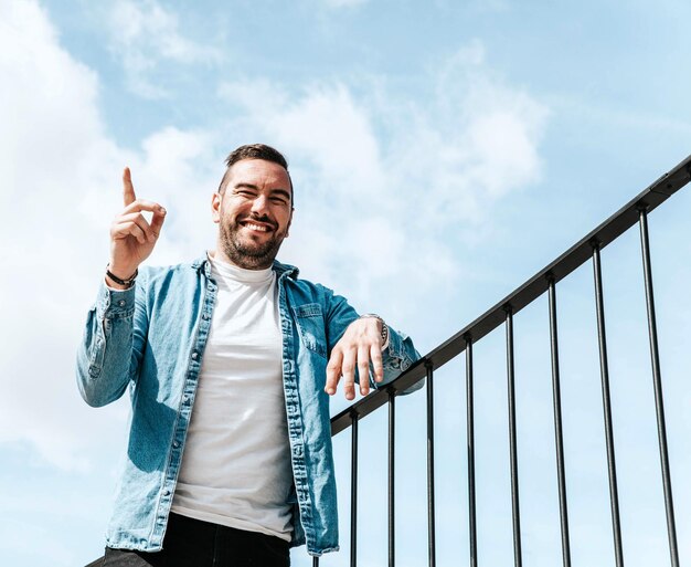 Ritratto di un bell'uomo hipster in una giacca di jeans in una grande città per strada un concetto di stile di vita