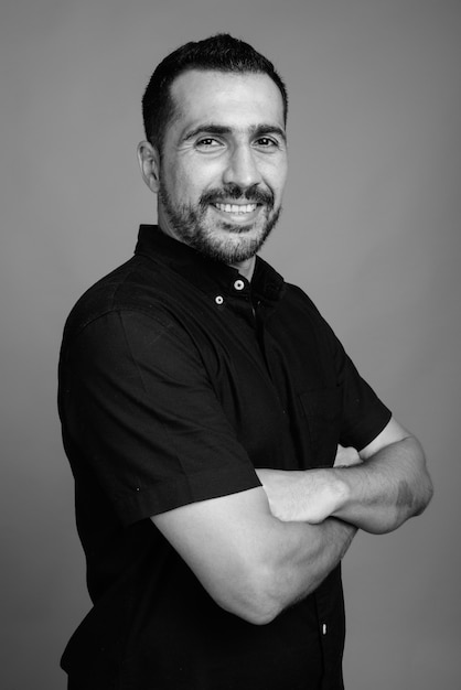 Ritratto di un bell'uomo persiano barbuto che indossa una camicia nera su grigio in bianco e nero