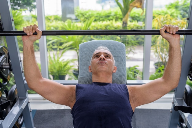 Ritratto di un bell'uomo persiano maturo con i capelli grigi che si esercita in palestra