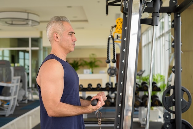 Ritratto di un bell'uomo persiano maturo con i capelli grigi che si esercita in palestra