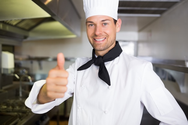 Ritratto di un cuoco maschio sorridente che gesturing i pollici su