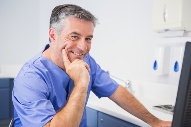 Ritratto di un dentista sorridente che per mezzo del computer