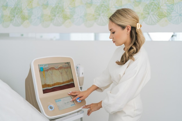 Ritratto di un'estetista specialista femminile che regola l'apparecchio per il sollevamento di smas prima della procedura in una clinica di medicina estetica