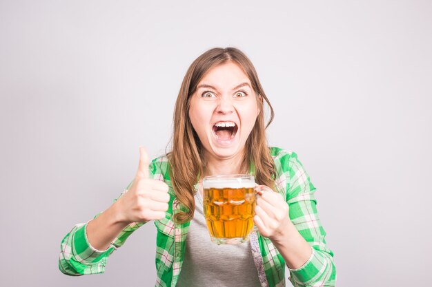 Ritratto di un euforico appassionato di sport con in mano una bottiglia di birra. Donna con birra.