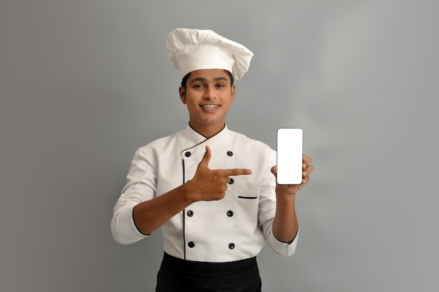 Ritratto di un felice chef maschio vestito in uniforme che tiene Mobile e puntamento