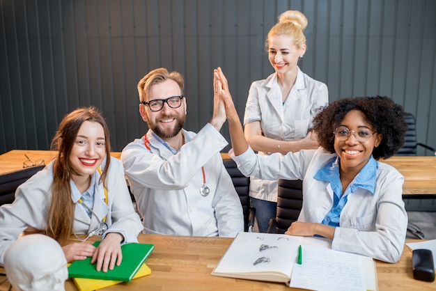 Ritratto di un felice gruppo multietnico di scienziati medici o studenti seduti insieme in ufficio o in classe