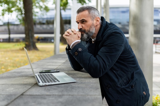 Ritratto di un finanziere maschio adulto maturo con i capelli grigi e la barba che guarda pensieroso di lato