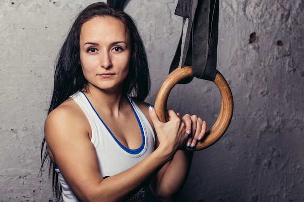 Ritratto di un fitness woMan formazione braccia con anelli di ginnastica in palestra