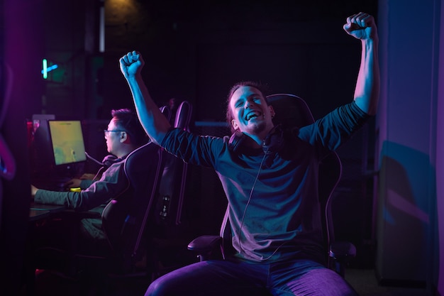 Ritratto di un giocatore eccitato seduto su una sedia e godersi la sua vittoria in un gioco per computer