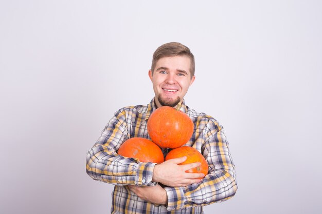 Ritratto di un giovane agricoltore che tiene un zucche su uno sfondo chiaro studio.