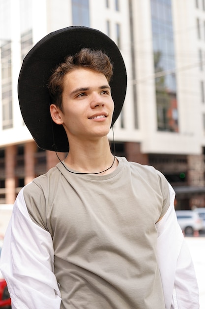 Ritratto di un giovane alla moda in città. primo piano ritratto ragazzo modello in un cappello nero per strada