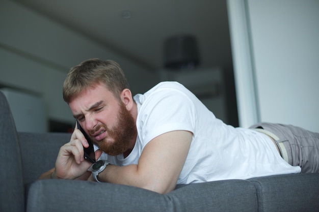 Ritratto di un giovane arrabbiato, triste, sconvolto, frustrato, uomo insoddisfatto, infelice, ragazzo che parla, giura sul cellulare.