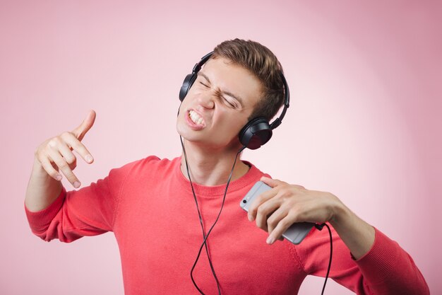 Ritratto di un giovane bell'uomo con le cuffie che sorride e ascolta una musica