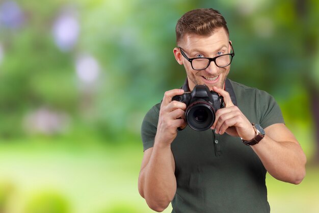 Ritratto di un giovane bello in occhiali uomo con fotocamera