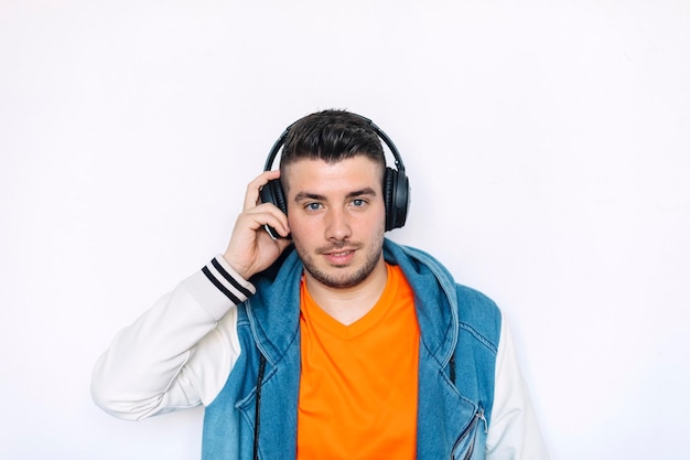 Ritratto di un giovane che ascolta musica in piedi su uno sfondo bianco